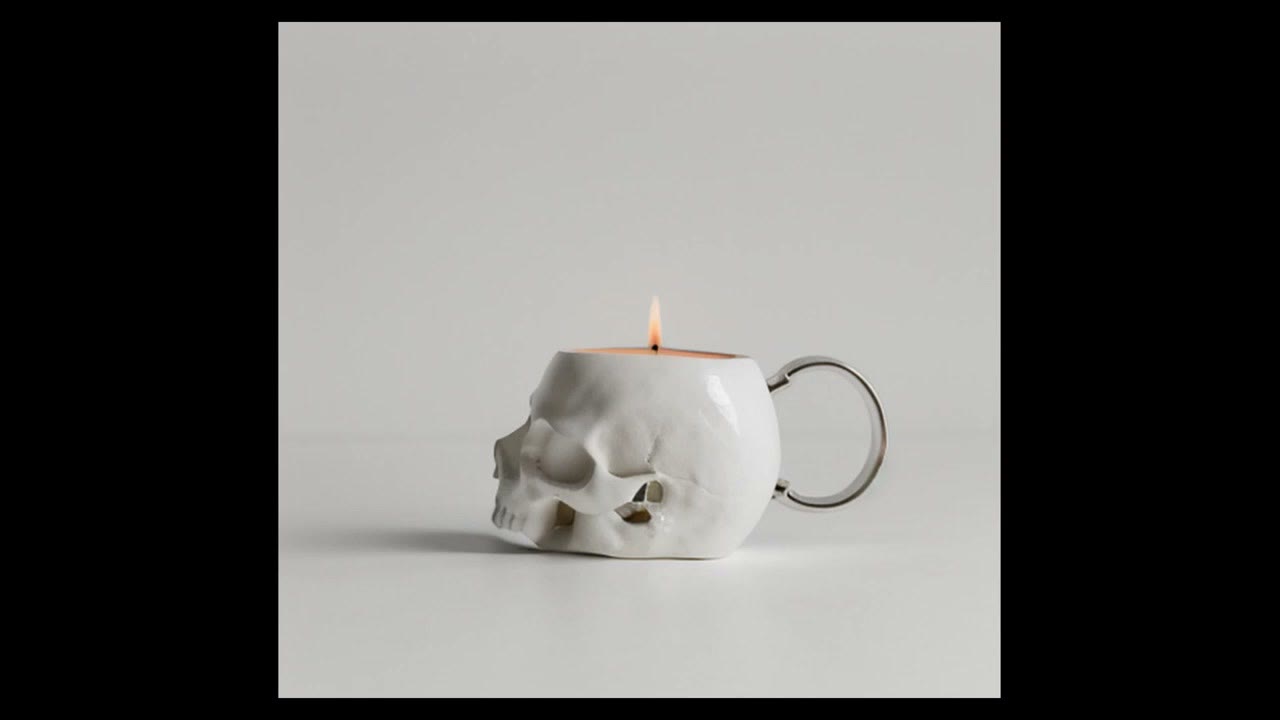 A skull teapot with a lit candle on top